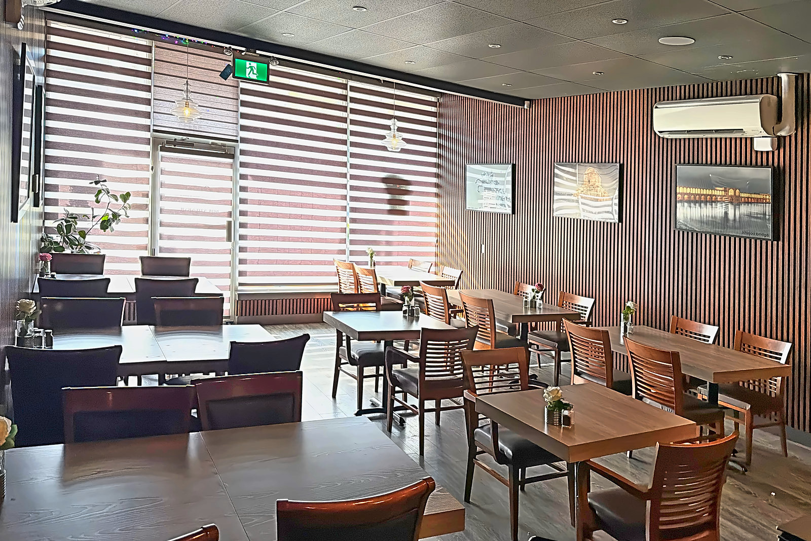 Avishan restaurant dining room with wood-slat walls and Persian art photos, seating for group dinners
